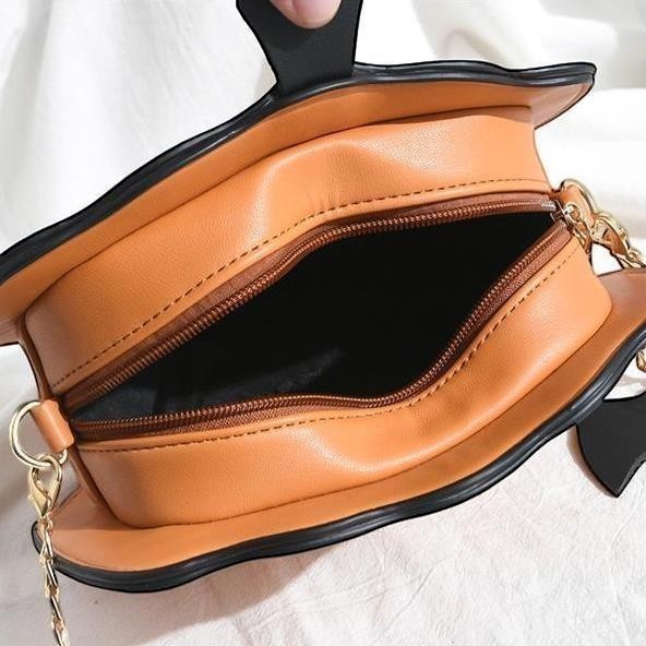 Pordein orange PU leather Halloween pumpkin handbag with black trim and gold chain strap.