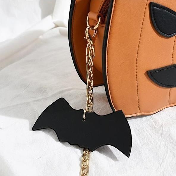 Pordein orange PU leather Halloween pumpkin handbag with black bat keychain and gold chain strap.