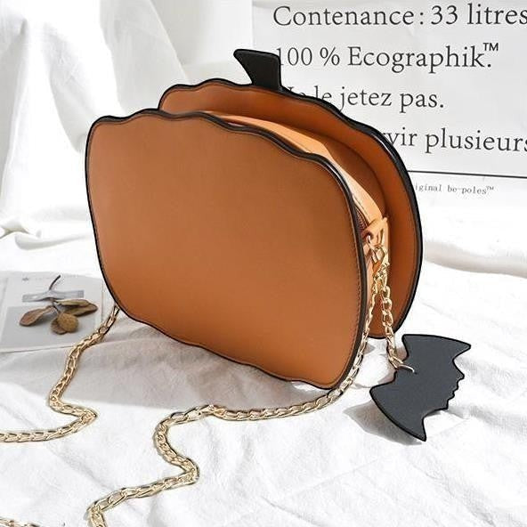 Pordein orange PU leather Halloween pumpkin handbag with gold chain strap and bat keychain.