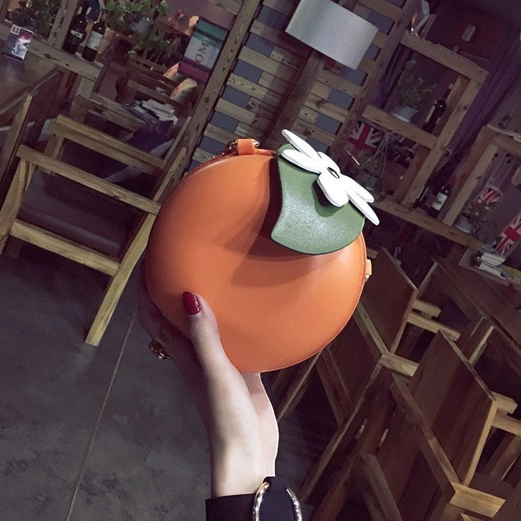 Pordein orange vegan PU leather mini bag shaped like a persimmon with a white flower detail. Can be worn as a handbag or clutch.