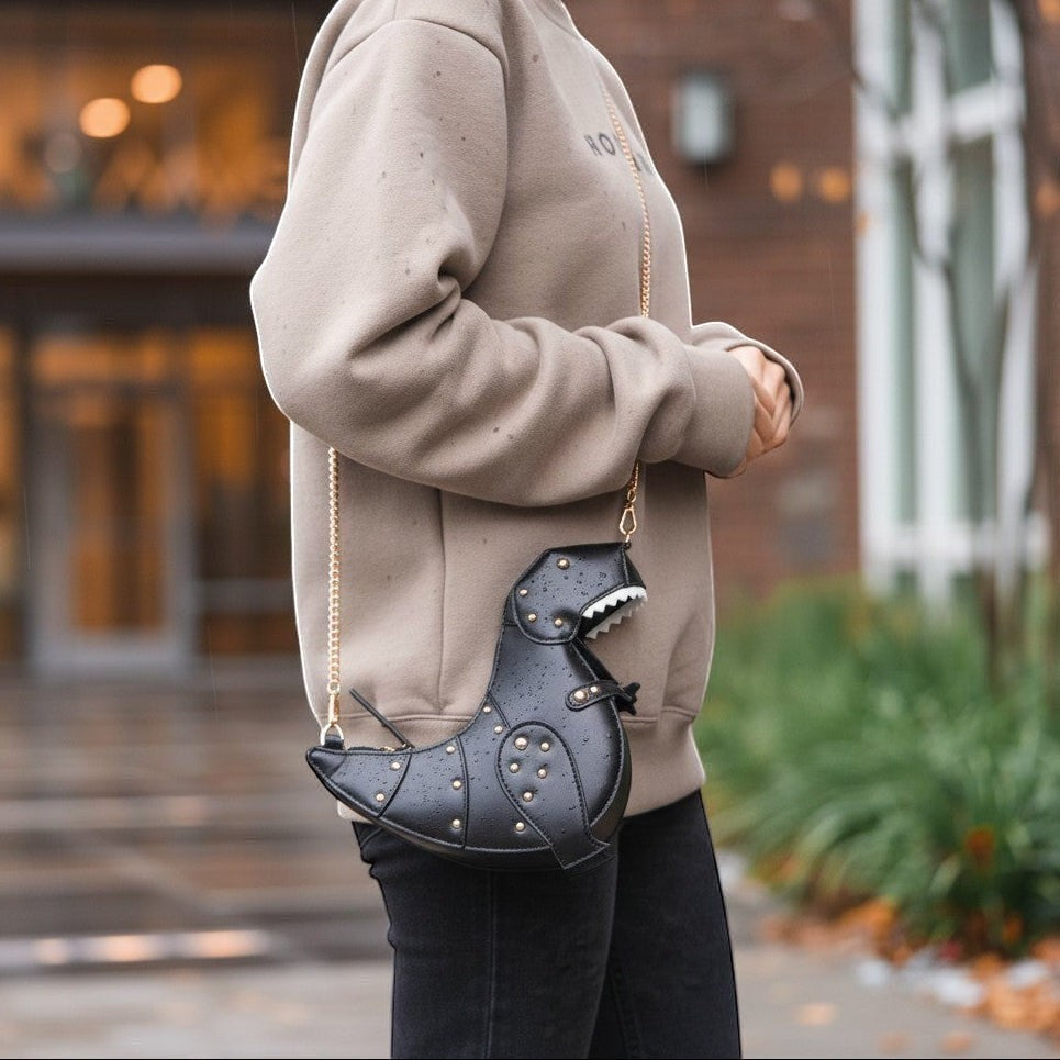 Pordein black vegan leather Rex Mini Bag shaped like a dinosaur with gold studs and chain strap.