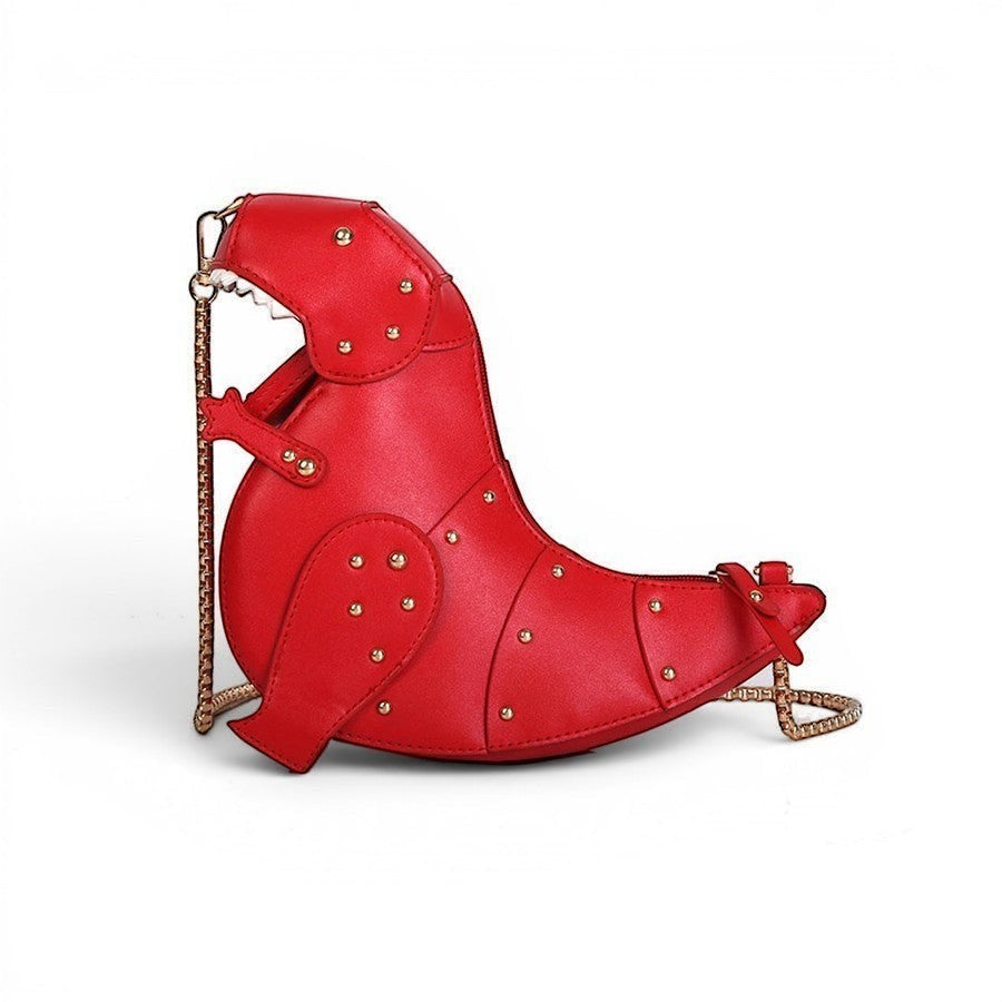 Pordein Rex Mini Bag, a red vegan leather crossbody bag shaped like a dinosaur with gold stud detailing and a chain strap.