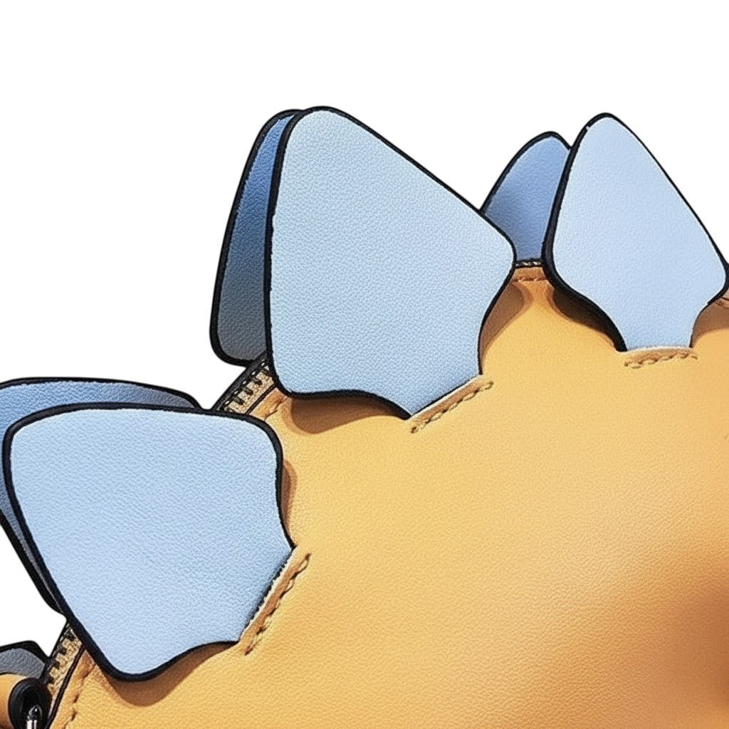 Pordein Stegosaurus Mini Bag in yellow vegan leather with light blue plates and black trim. Zippered compartment.